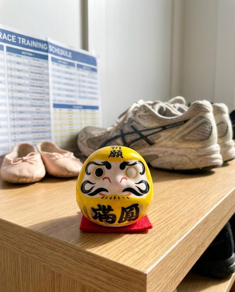 A one-eyed yellow Daruma on a kitchen windowsill above the sink