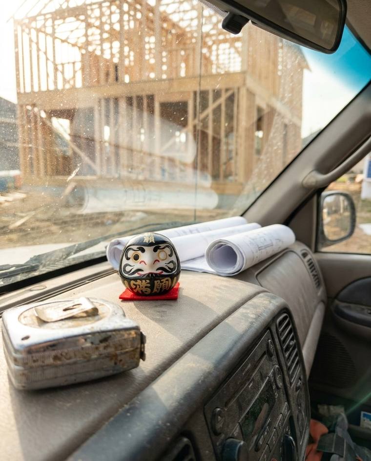A black one-eyed Daruma on the dashboard of Chris's work truck
