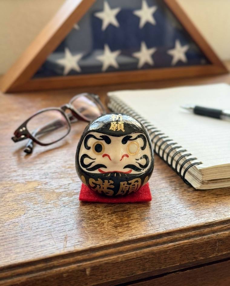 A one-eyed black Daruma on the windowsill above Frank's kitchen sink