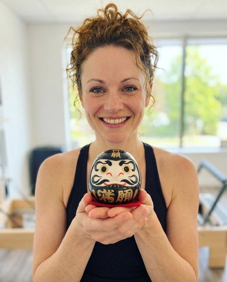 Hannah painting the second eye of the black Daruma on the floor of her own studio