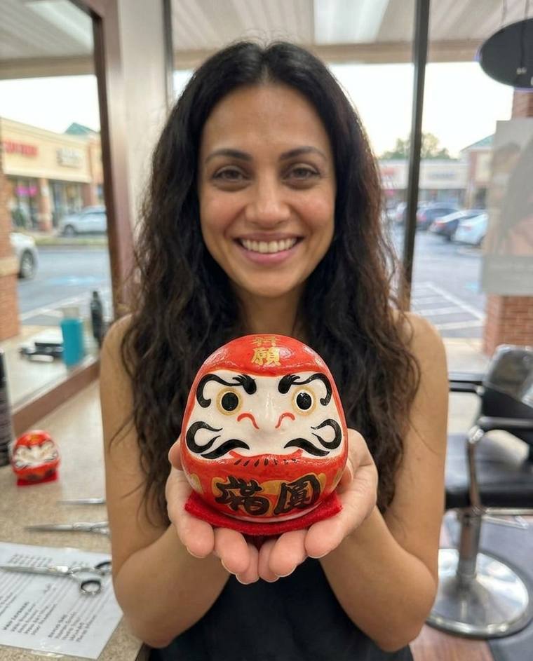 Cindy inking the second eye of the red Daruma on the floor of her new studio