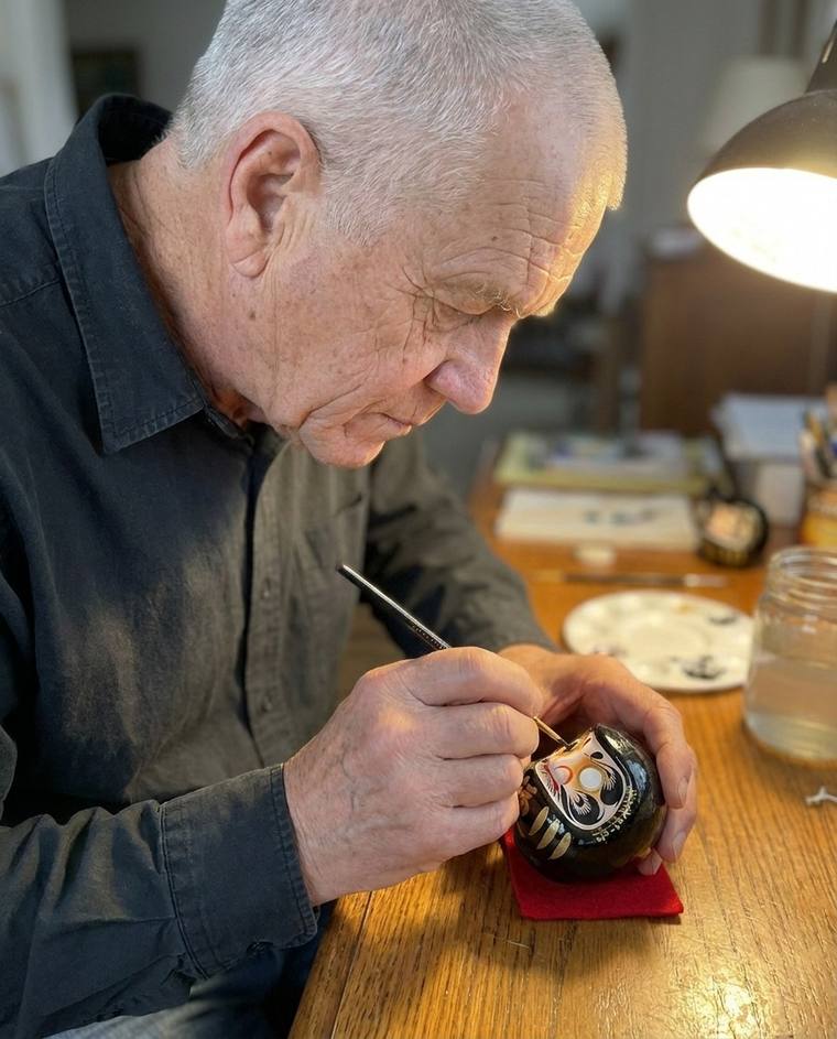 Frank filling in the first eye of a black Daruma at his kitchen sink