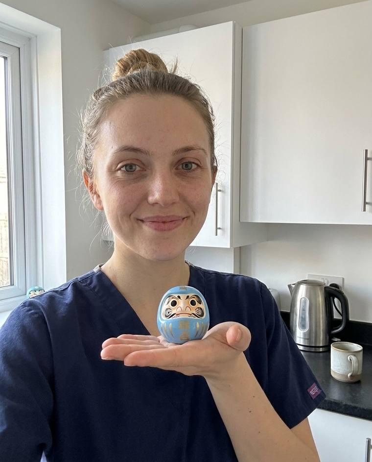 Megan painting the second eye of the blue Daruma in the hospital parking lot